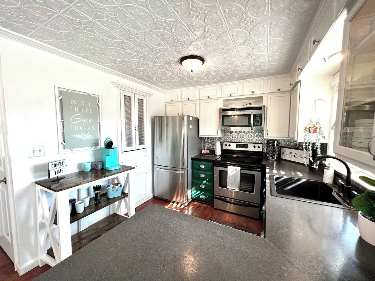 A modern kitchen with white cabinetry, stainless steel appliances, and a decorative ceiling.