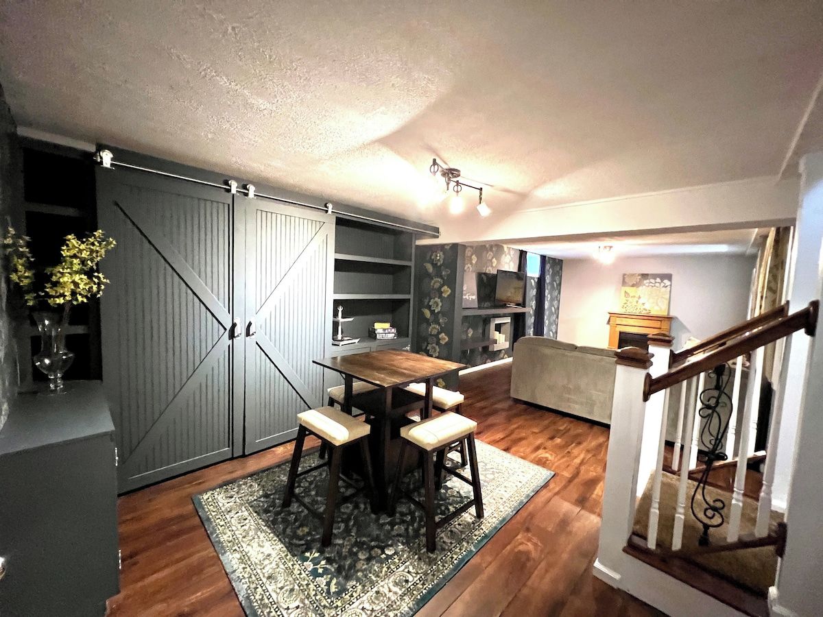 A dining area with a wooden table and four chairs, a sliding door closet, a kitchen with a microwave, and a staircase.
