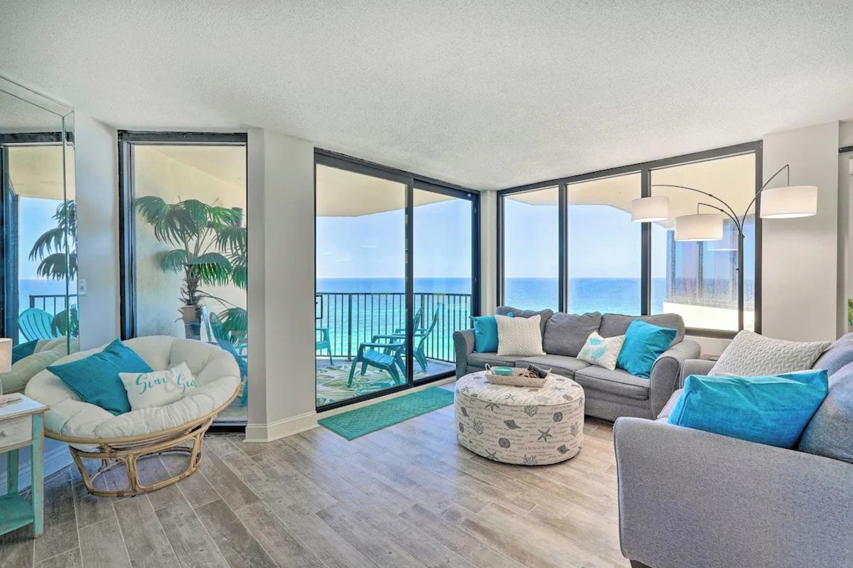 Un vaste espace de vie avec un balcon donnant sur la mer, aménagé avec un canapé, des fauteuils et une petite table.