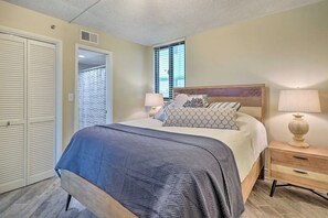Une chambre à coucher avec un lit, des tables de chevet, une armoire et une fenêtre avec des stores.