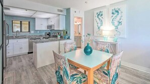A modern kitchen with white cabinets, a central island, and a dining area with a table and chairs.