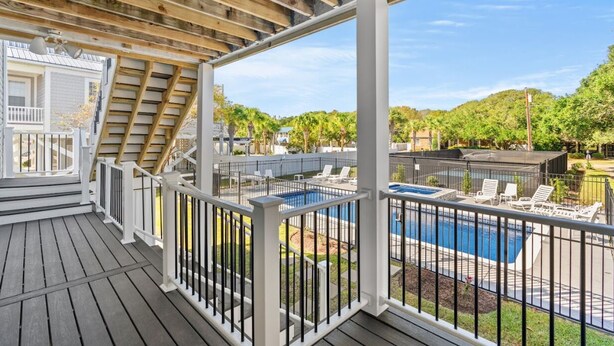A wooden deck with a pool, white railings, and a covered area with a staircase. - Long Bay Duplex Lower Unit by the Beach (Surfside Beach)