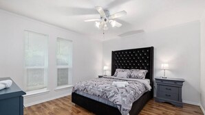 A bedroom with a bed, a ceiling fan, two bedside tables, and a window with blinds. - Stylish 5BR 3BA Home w/Pool Perfect for 16ppl (Allen)