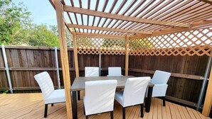 An outdoor patio with a wooden deck, a table with six chairs, and a wooden pergola overhead. - Stylish 5BR 3BA Home w/Pool Perfect for 16ppl (Allen)