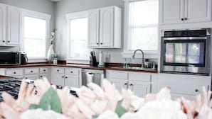 A modern kitchen with white cabinets, a stainless steel oven, and a microwave. - 3 Bedroom Cozy Home with the Perfect Patio (Winter Haven)