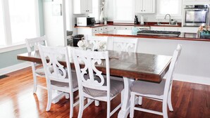 A kitchen with white cabinets, a wooden dining table, and white chairs. - 3 Bedroom Cozy Home with the Perfect Patio (Winter Haven)