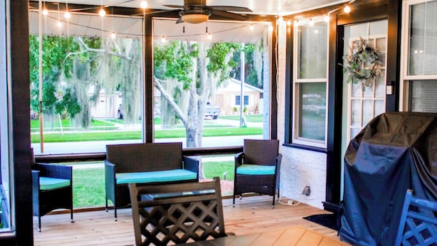 A covered outdoor seating area with wicker furniture and a view of a residential neighborhood. - 3 Bedroom Cozy Home with the Perfect Patio (Winter Haven)