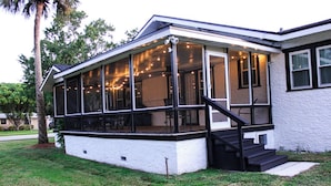 A house with a covered porch, a staircase leading to the entrance, and a well-maintained lawn. - 3 Bedroom Cozy Home with the Perfect Patio (Winter Haven)