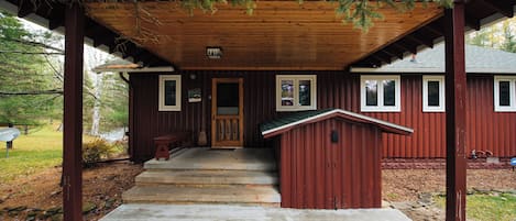 A wooden cabin with a porch, steps leading to the entrance, and a small shed.