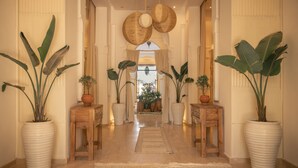 A hallway with large potted plants, wooden tables, and a patterned rug. - Les Palmiers Boutique Hôtel & Spa (Marrakech)