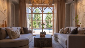 A modern living room with two sofas facing a large window, a round coffee table, and a decorative wall piece. - Les Palmiers Boutique Hôtel & Spa (Marrakech)