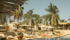 A poolside area with lounge chairs, umbrellas, and potted plants. - Les Palmiers Boutique Hôtel & Spa (Marrakech)