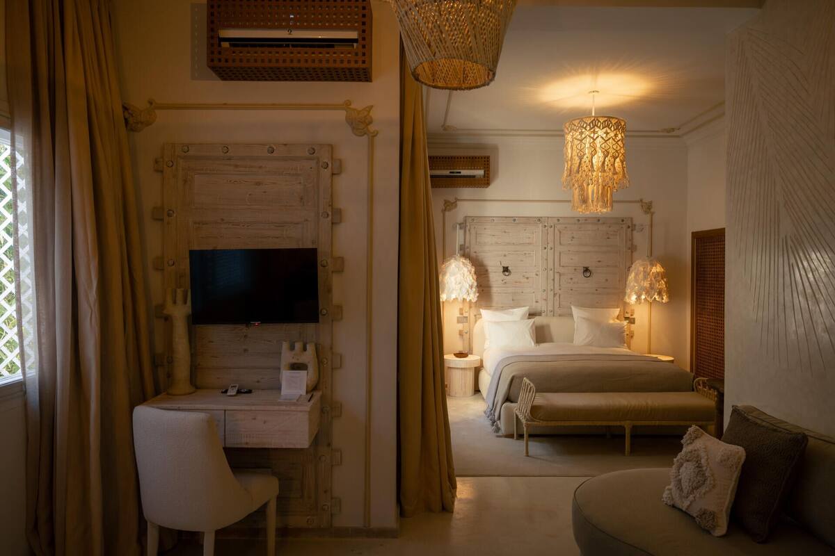 Een slaapkamer met een bed, nachtkastjes, een bureau, een stoel en een televisie.