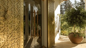 A traditional architectural entrance with intricate metalwork, a large potted plant, and a view of greenery outside. - Les Palmiers Boutique Hôtel & Spa (Marrakech)