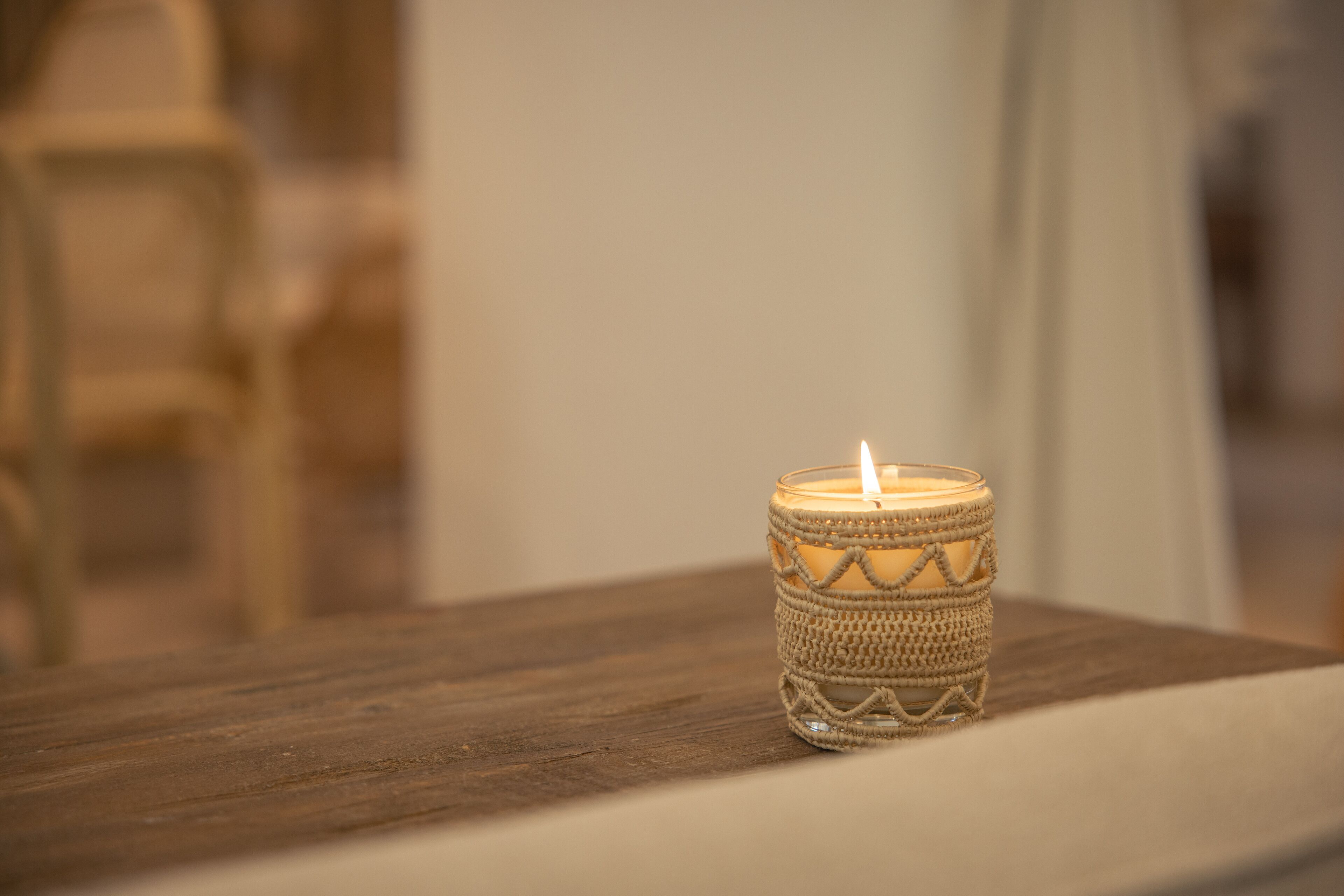 Una vela en un soporte de vidrio con textura sobre una superficie de madera.