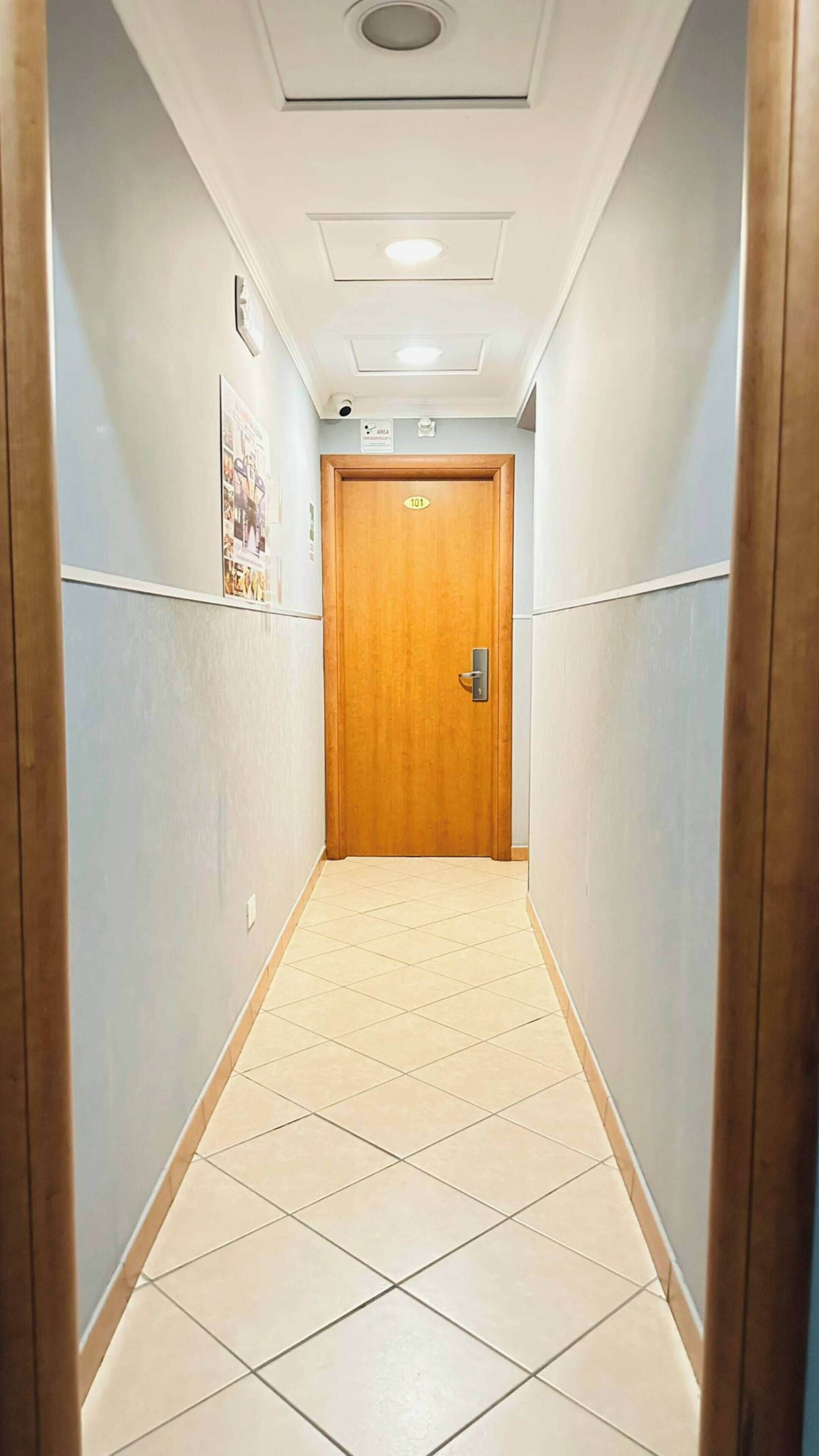 A narrow, tiled hallway with a wooden door marked '101'.