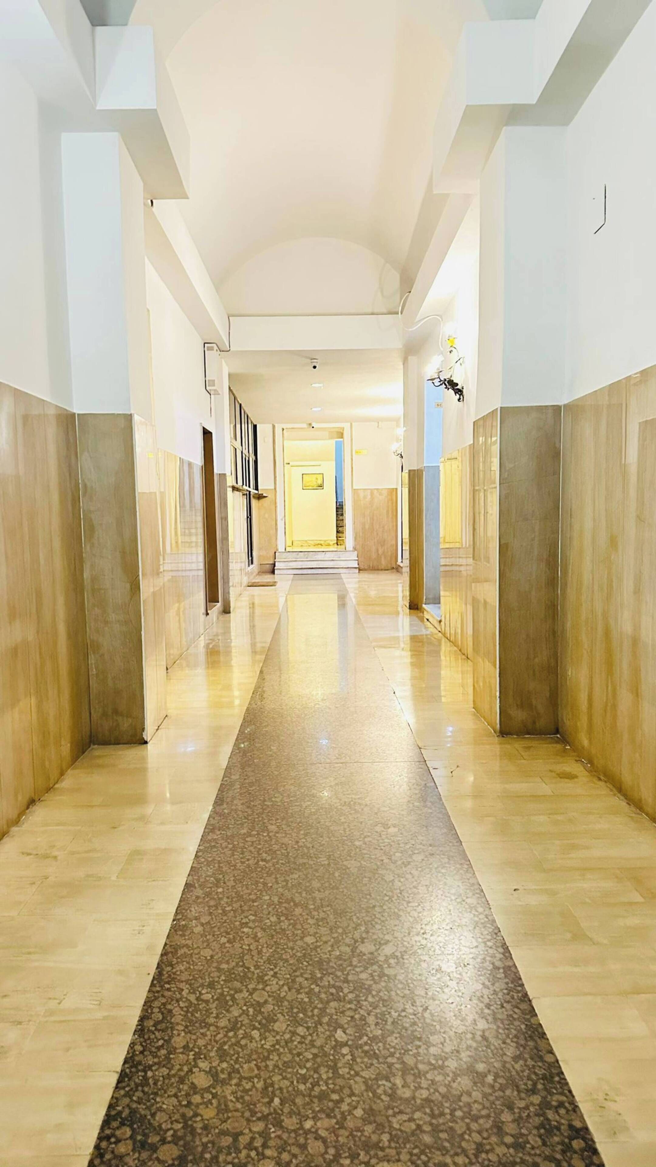A long, narrow hallway with a polished stone floor and light-colored walls.