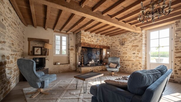 A rustic living room with exposed wooden beams, a stone wall, a fireplace, and a comfortable seating area. - Ferme Sarthou, 14 Personnes, Avec Piscine, 5 Étoiles (Lucq-de-Béarn)