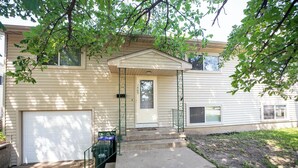 A two-story house with a front porch, a garage, and a small front yard.