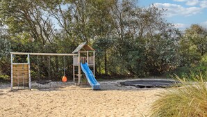 Une aire de jeux avec un toboggan, une balançoire et un trampoline.