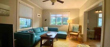 Un salon avec un canapé, une table basse et un ventilateur de plafond.