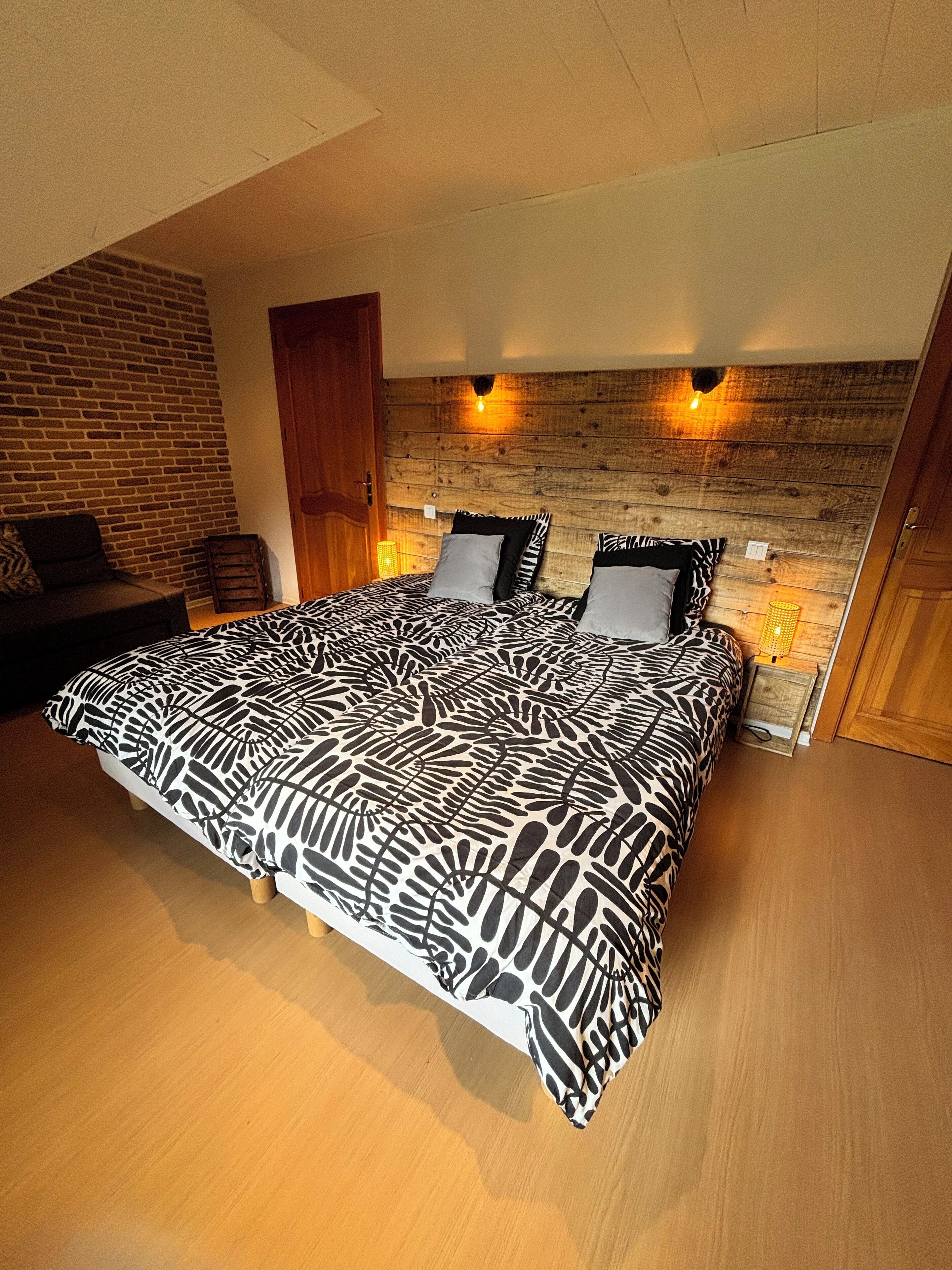 Un dormitorio con una cama grande, cabecera de madera y dos luces fijadas a la pared.