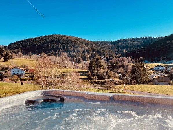 Uma banheira de hidromassagem com vista para uma paisagem rural, incluindo casas e colinas.