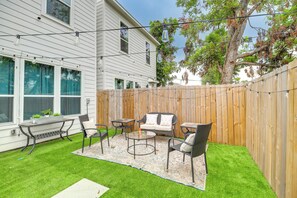 A backyard with a wooden fence, a patio with outdoor furniture, and a lawn. - Modern Houston Home w/ Yard, 3 Mi to Toyota Center (Houston)