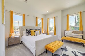 A bedroom with a large bed, a bedside table, a bench, and a view of the outside. - Modern Houston Home w/ Yard, 3 Mi to Toyota Center (Houston)