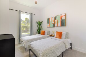 A modern bedroom with two beds, a large window, and abstract wall art. - Modern Houston Home w/ Yard, 3 Mi to Toyota Center (Houston)