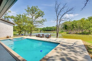 A rectangular swimming pool with a clear blue water, surrounded by a concrete deck. There are lounge chairs and a small table on the deck. - Relax Fireside! Waterfront Malakoff Home w/ Pool (Malakoff)