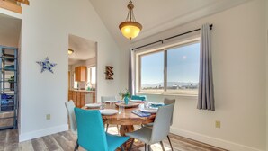 Un comedor con una mesa de madera, cuatro sillas y vistas al exterior a través de un ventanal grande.