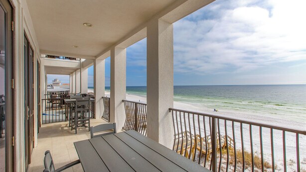 A covered outdoor area with tables and chairs, overlooking a beach with a clear view of the ocean and a distant ship. - Dos Casas - Gulf-front Home with 2 Martini Pools and Beach Service (Destin)