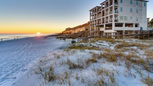 A beachfront hotel with multiple floors, outdoor staircases, and a view of the ocean at sunset. - Dos Casas - Gulf-front Home with 2 Martini Pools and Beach Service (Destin)