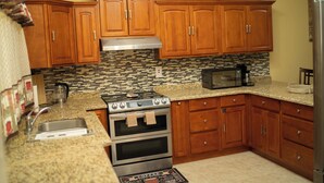 Una cocina con armarios de madera, una estufa de acero inoxidable, un microondas y un salpicadero de azulejos.