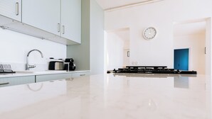 Una cocina moderna con armarios blancos, un lavamanos de acero inoxidable y una estufa negra.