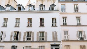 Una hilera de edificios blancos con múltiples ventanas y balcones, que presentan un estilo arquitectónico uniforme.