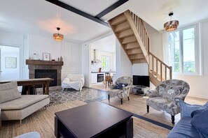 Amplia sala de estar con chimenea, escalera y televisor.