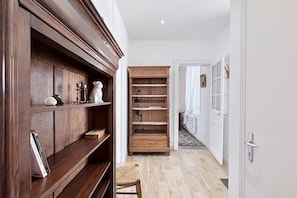 A hallway with wooden shelves, a chair, and a door leading to another room.