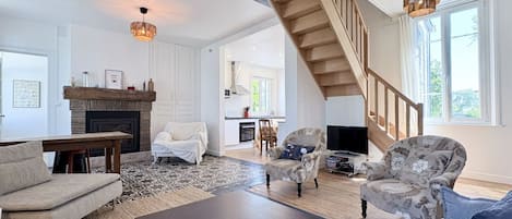 A spacious living room with a fireplace, a staircase, and a television.