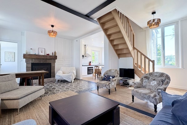 Un salon spacieux avec une cheminée, un escalier et un téléviseur.