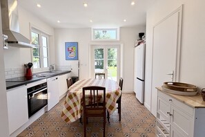 Une cuisine équipée d’une table à manger, de chaises, d’un réfrigérateur et d’une fenêtre.