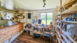 A rustic interior with wooden furniture, a kitchen area, and shelves stocked with various items.