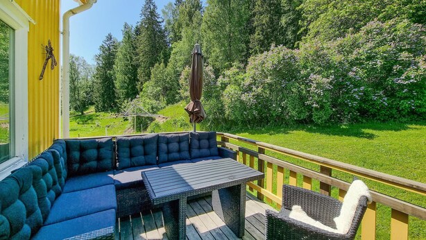 A deck with a blue sofa and a table, surrounded by a wooden railing.