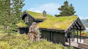 Ein traditionelles Holzhaus mit einem Reetdach, einem Steinofen und einer Holzterrasse mit Sitzgelegenheit.