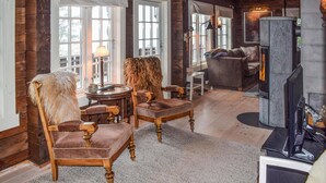Una sala de estar acogedora con chimenea, muebles de madera y ventanas amplias.