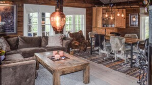 Una sala rústica con una mesa de centro de madera, un sofá de cuero y un comedor con sillas de metal.