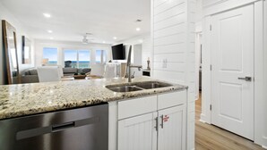 A modern kitchen with granite countertops, stainless steel appliances, and white cabinetry.
