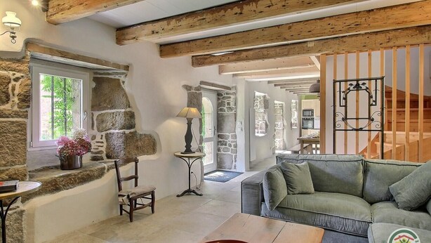 A rustic interior with exposed wooden beams, stone walls, a green sofa, a wooden table, and a lamp. - Kerguntuil - Pleumeur Bodou (PLEUMEUR BODOU)
