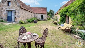A courtyard with stone buildings, a table with chairs, and a bench. - Kerguntuil - Pleumeur Bodou (PLEUMEUR BODOU)